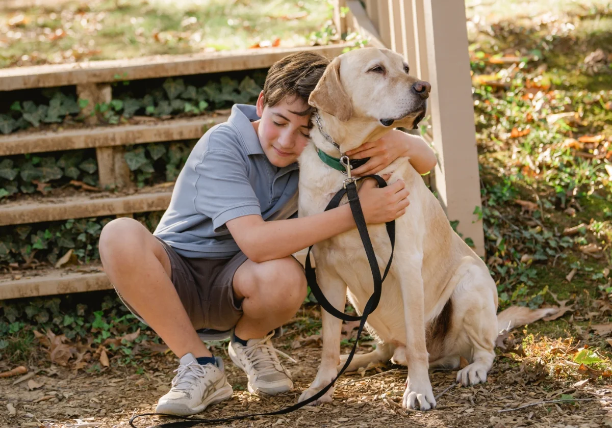 student hugging school service dog