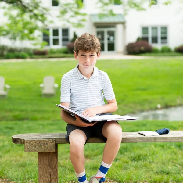 student sitting outside reading a book