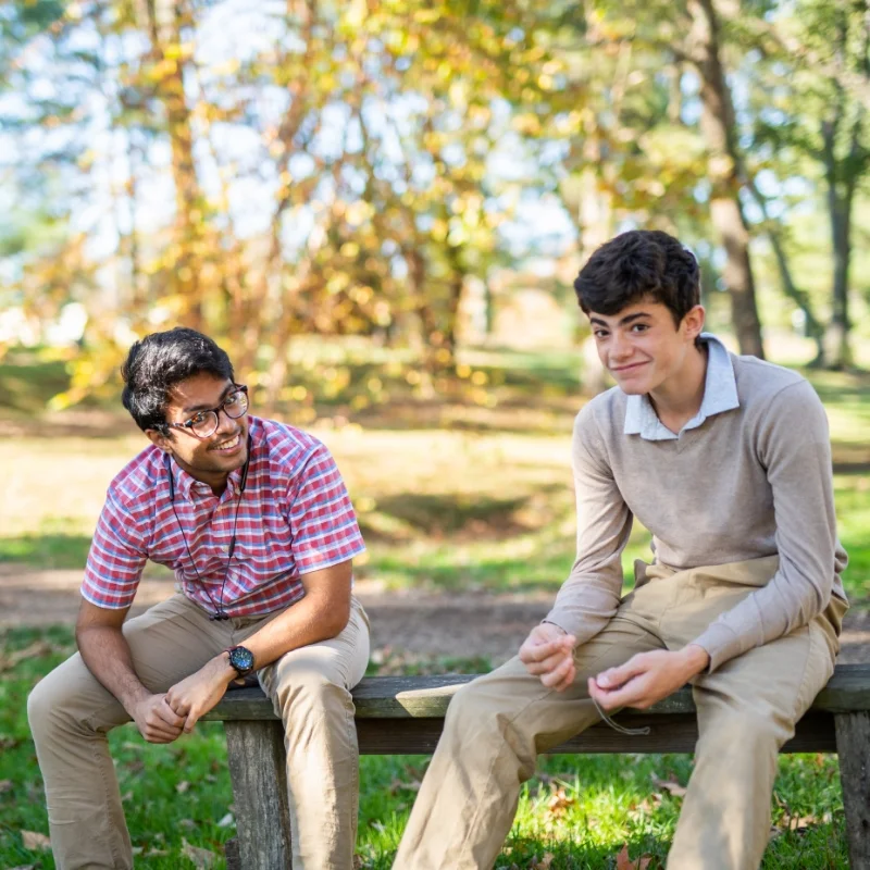two students talking on an outdoor bench