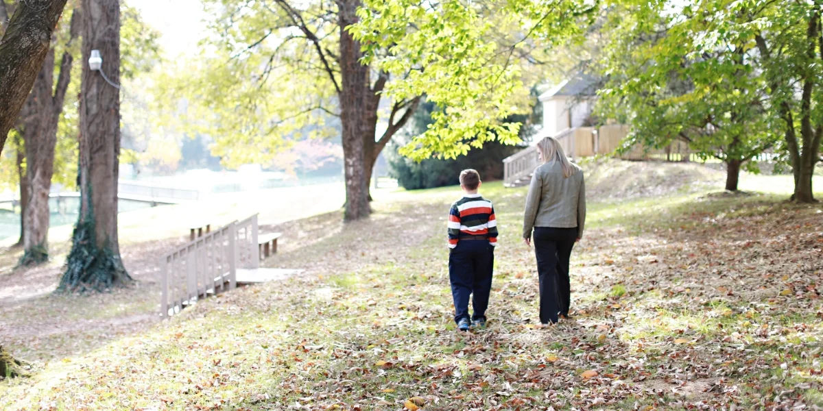 teacher and student walking through fallen leaves
